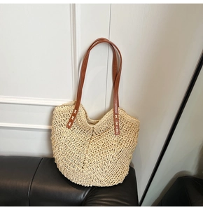 Gros plan du sac en paille tissée avec anses en cuir marron et couture croisée