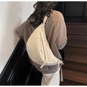 Detail of cream crescent crossbody bag with woven knot zipper on a model