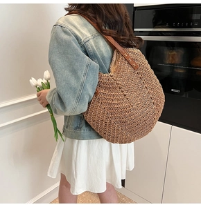 Détail d'un sac à bandoulière en paille avec des lanières en cuir et texture tressée
