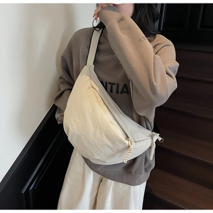 Detail of a beige dumpling-style crossbody bag showing the nylon fabric and wide strap