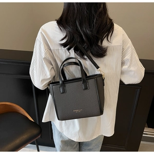 Detailed view of the woven black bucket bag texture and the golden brand logo on a crossbody strap