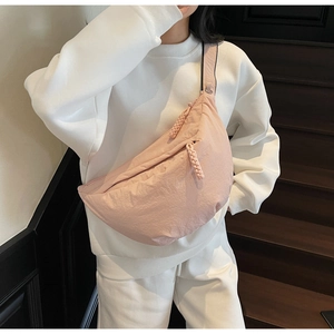 Detail of pink crescent crossbody bag with braided rope zipper on a white hoodie