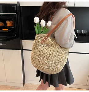 Détail du sac cabas en paille tissé avec bandoulière en cuir et tulipes blanches