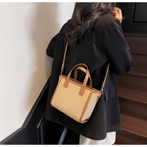 Straw weave tote bag with brown leather trim shown in a stylish indoor lifestyle setting