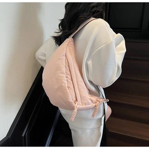 Back view of light pink crescent crossbody bag worn by model on stairs