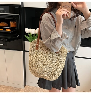 Détail d'un sac cabas en paille tressée avec anses en cuir marron et tulipes décoratives