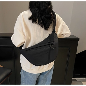 Model wearing a large black nylon crossbody bag with casual urban dumpling shape style