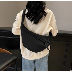 Detail of black crossbody dumpling bag featuring a thick woven rope zipper and nylon texture