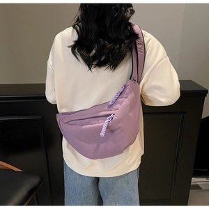 Detail of purple nylon crescent bag with adjustable strap and textured pleats on model