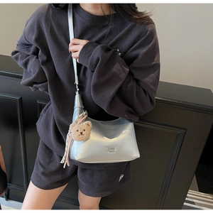 Silver metallic hobo shoulder bag with a cute brown bear plush pendant and sleek strap