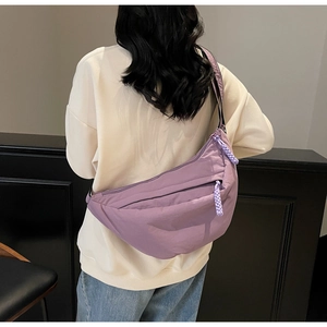 Detailed macro view of purple crescent crossbody bag featuring woven rope zipper pullers