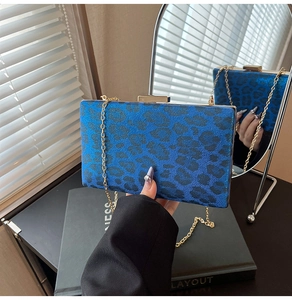 Dettaglio di una pochette da sera blu leopardata con catena dorata e chiusura in metallo
