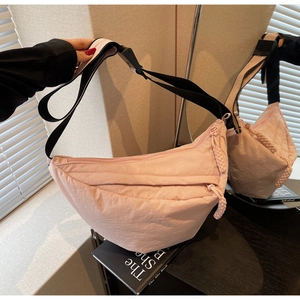 Detail of pink nylon half-moon crossbody bag with textured fabric and black buckle strap