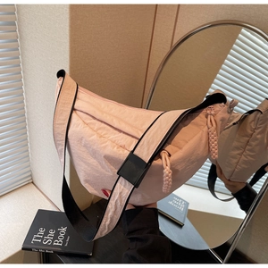 Detailed close-up of light pink nylon crescent bag with adjustable black shoulder strap