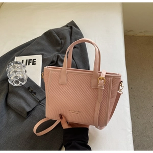 Close-up of pink woven texture bucket bag with adjustable strap and gold hardware accents