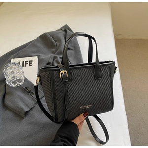 Detail showing woven texture and smooth leather strap of the black bucket tote bag