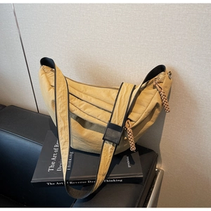 Detail of mustard yellow dumpling bag featuring textured fabric and woven zipper pullers