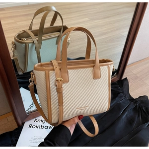 Detail of a beige woven tote bag with brown leather trim and a mirror reflection