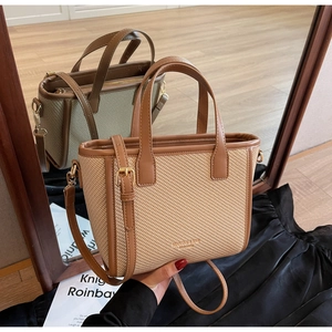 Detail of woven bucket bag with leather handles and metallic hardware shown in a mirror