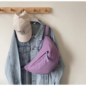 Detail of lavender crescent crossbody bag featuring textured nylon and woven zipper pull