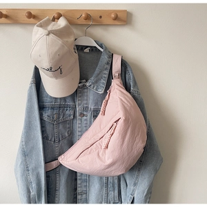 Pink half-moon crossbody bag detail with textured nylon fabric and braided zipper pulls