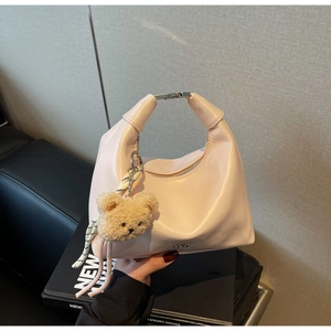 Pink crescent handbag detail with silver hardware and a cute brown plush bear keychain