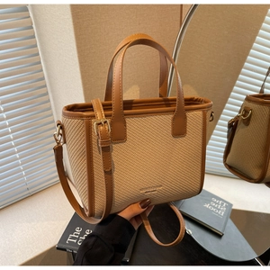 Close-up of woven bucket bag featuring brown faux leather trim and adjustable strap