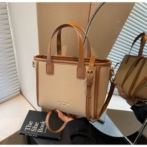 Detail of minimalist woven bucket bag with brown leather trim and adjustable strap