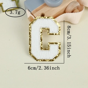 Detailed view of chenille letter C patch with gold glitter edge and white towel texture