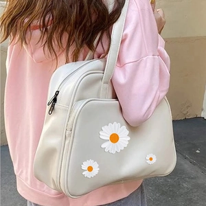 Detail eines weißen Gänseblümchen-Stickpatches auf einer cremefarbenen Ledertasche