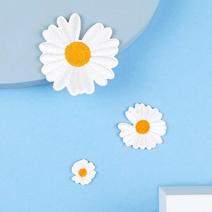 Detailaufnahme von drei Gänseblümchen-Stickpatches in verschiedenen Größen auf Blau