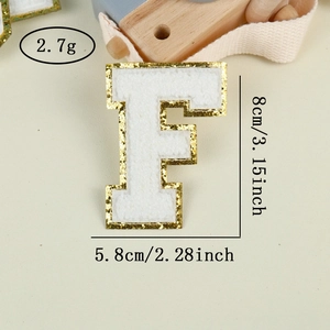 Detail of chenille letter F patch with gold glitter edge and embroidery texture