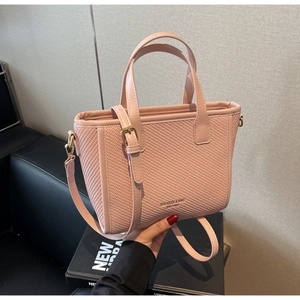 Detail of pink woven leather bucket bag with top handles and adjustable shoulder strap