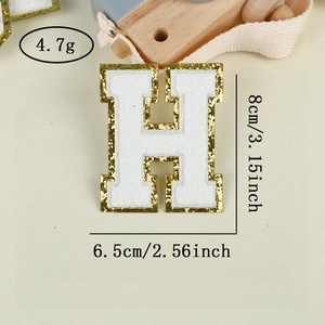 Macro view of white chenille letter H patch with gold sequins and size dimensions