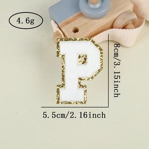 Macro shot of gold sequin letter P patch with white embroidery for DIY decor