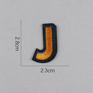 Détail de l'écusson brodé lettre J doré montrant les dimensions 2,8cm hauteur et 2,3cm largeur
