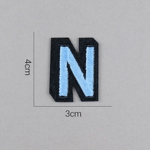 Détail de l'écusson brodé lettre N bleu clair avec support en feutre noir 4cm x 3cm