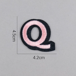 Détail d'un écusson brodé lettre Q rose avec bordure noire et dimensions de 4,5 cm