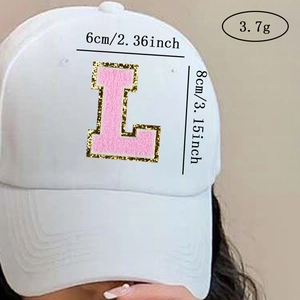 Detail of pink chenille letter L patch with gold glitter edge on white baseball cap
