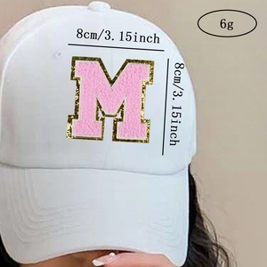 Detail view of pink towel embroidered M letter patch on white cotton baseball cap