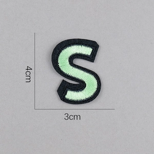 Détail d'un écusson brodé lettre S avec dimensions 4cm sur 3cm sur fond gris