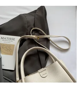 Detail of white lychee leather handbag with golden hardware and fashion logo