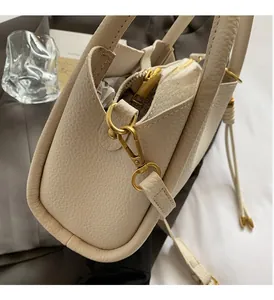 Detail of off-white lychee grain leather bucket bag with gold hardware and fine stitching