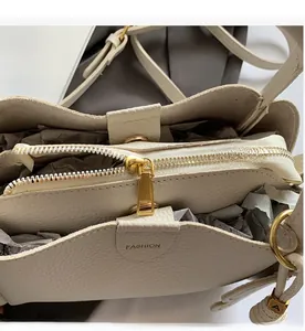 Detail of off-white lychee leather handbag featuring gold zipper and fashion embossing