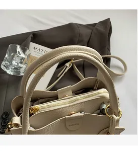 Detail view of beige pebbled leather handbag featuring gold hardware and fashion embossing