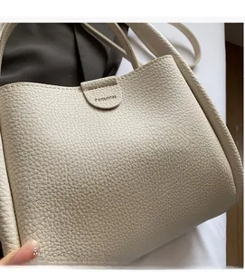 Close-up of off-white lychee pattern leather bucket bag with magnetic fashion closure
