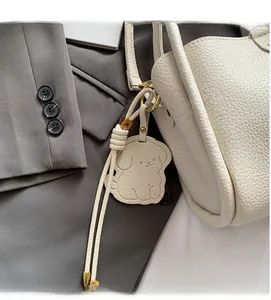 Close-up of white lychee leather bucket bag with a cute puppy charm and gold hardware