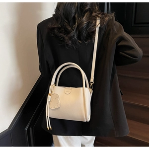Detail of cream white leather bucket bag with fashion embossing and puppy charm