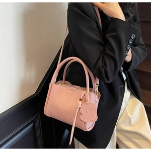 Pink lychee grain leather bucket bag with dog charm shown on a fashion model