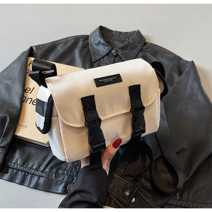 Detail of off-white nylon messenger bag with black buckle straps and brand label